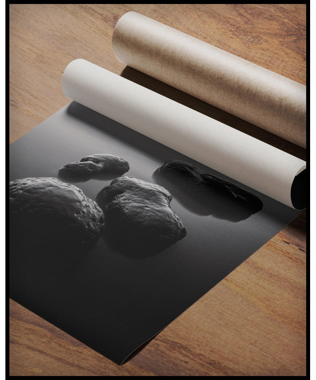 Ein Poster in schwarz-weiß von vier groben Steinen, die aus einem See herausragen, gerollt auf einer Holzoberfläche liegend