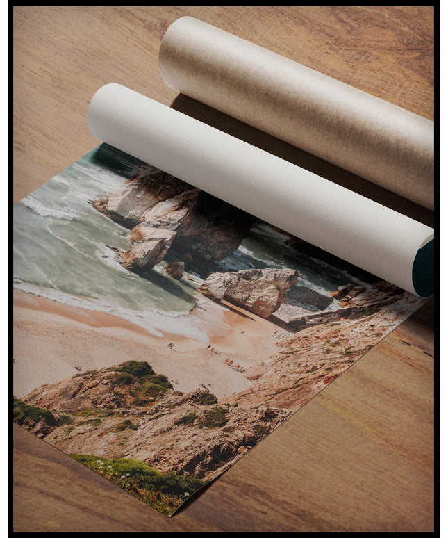 Ein Poster von hohen Felsformationen im Meer an einem Strand, gerollt auf einer Holzoberfläche liegend