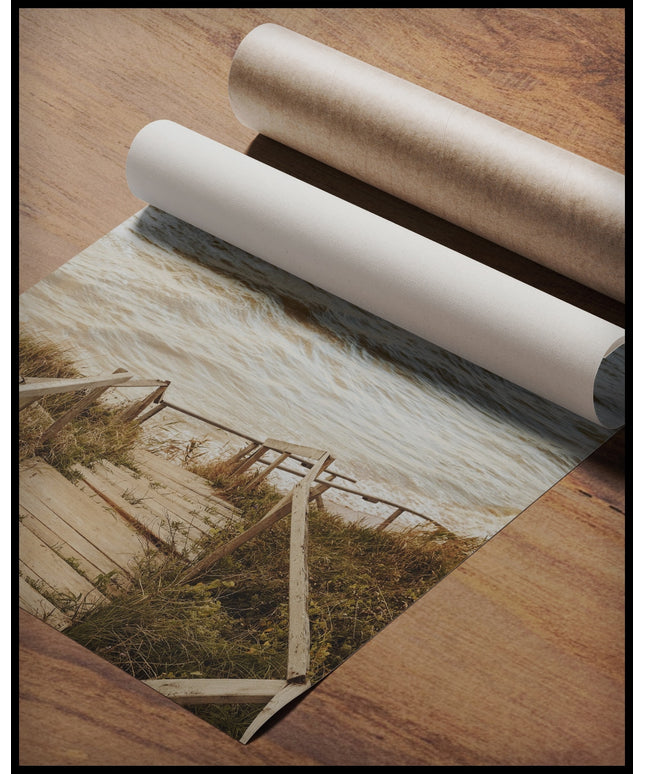 Ein Poster von einer Holztreppe die durch Dünen runter zum Strand führt, gerollt auf einer Holzoberfläche liegend