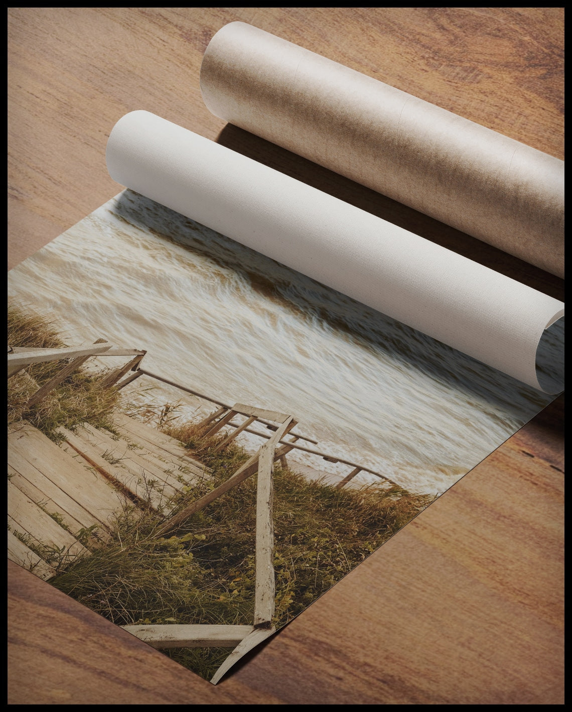 Ein Poster von einer Holztreppe die durch Dünen runter zum Strand führt, gerollt auf einer Holzoberfläche liegend