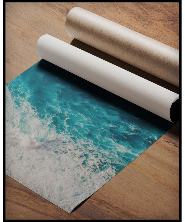 Ein Poster aus der Vogelperspektive vom blauen Meer und schaumigen Wellen, gerollt auf einer Holzoberfläche liegend