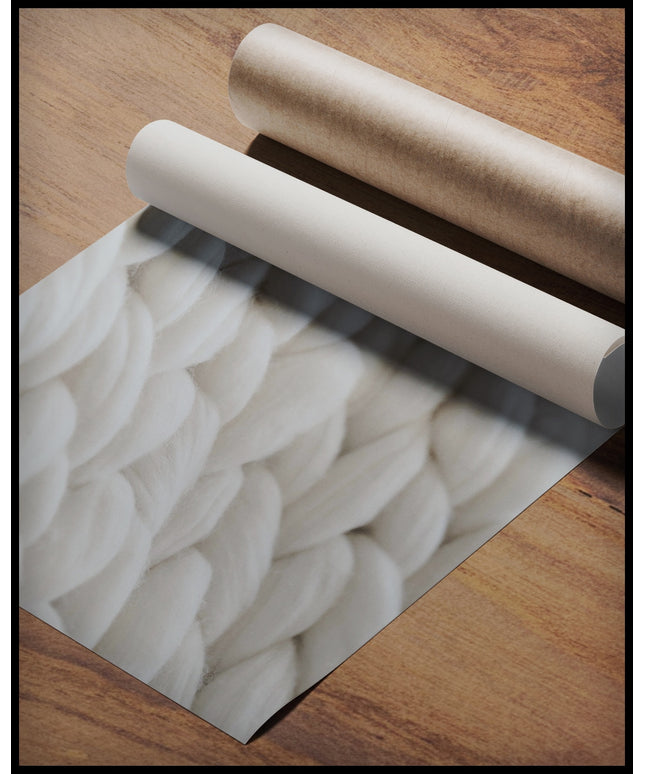 Ein Poster einer Nahaufnahme von den Maschen einer gewebten, weißen Wolldecke, gerollt auf einer Holzoberfläche liegend