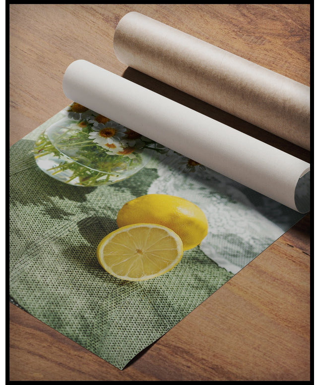 Ein Poster von zwei Zitronen und Blumen in einem Glas auf einer grünen Unterlage aus Stoff, gerollt auf einer Holzoberfläche liegend