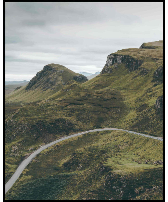 Ein Poster von einer Straße die an mehreren bewachsenen, kargen Bergen vorbei führt.