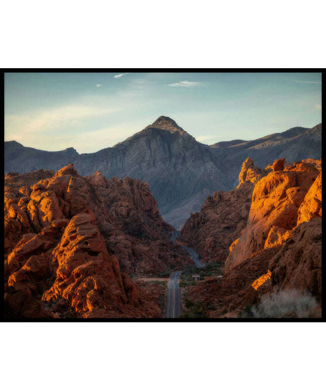 Ein Poster von einer Straße die durch ein steinernes Tal zu einem kargen Berg führt.