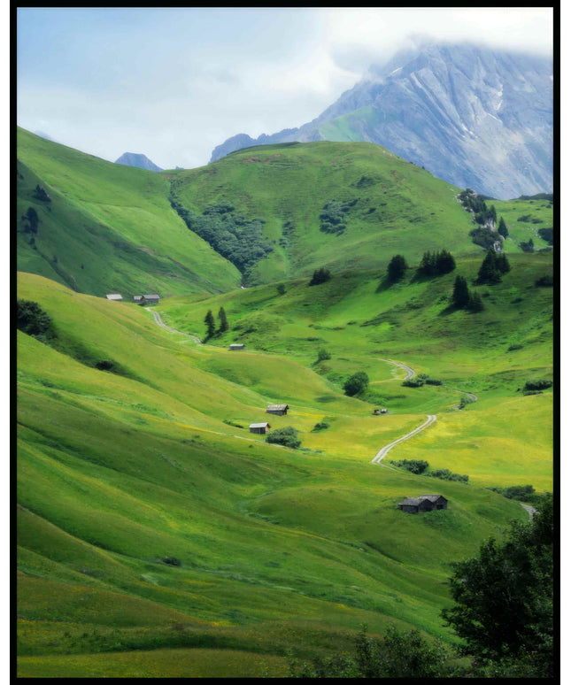 Ein Poster von einer grünen Berglandschaft mit einzelnen Bäumen und Holzhütten.