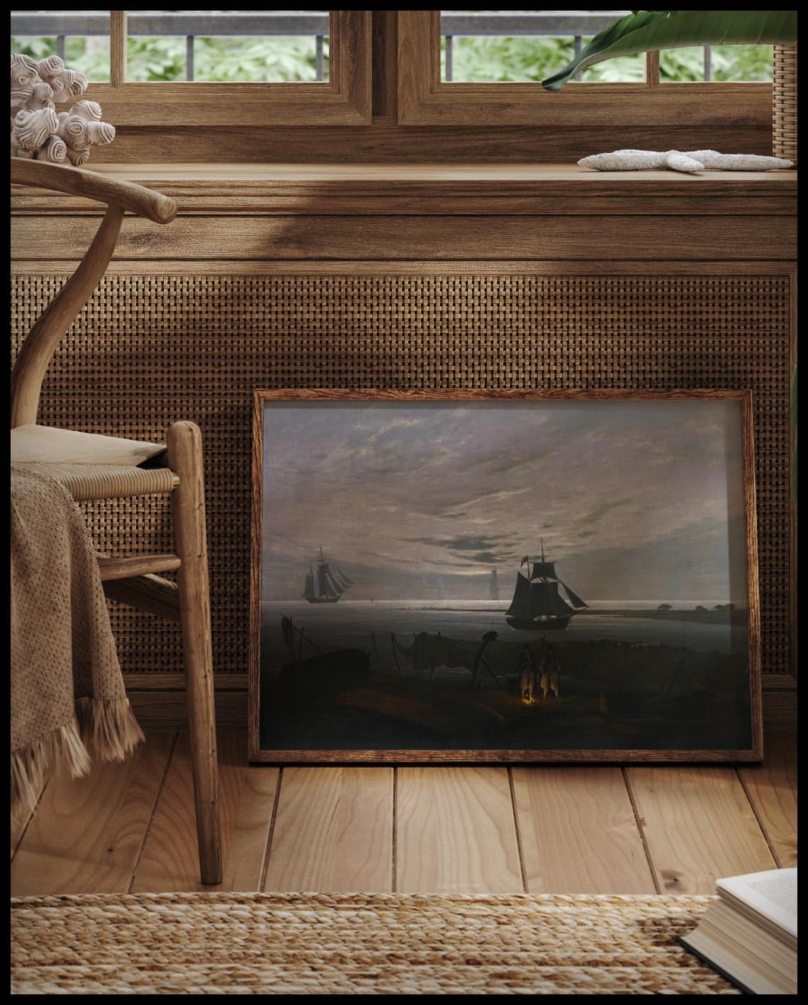Ein gerahmter Kunstdruck von einer Strandszene am Abend mit Schiffen im Hintergrund, vor einem Fenster an die Wand angelehnt