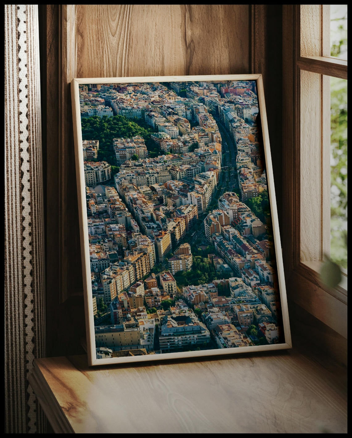 Ein gerahmtes Poster von einer langen Straße die durch die Innenstadt von Barcelona führt, vor einem Fenster an die Wand angelehnt
