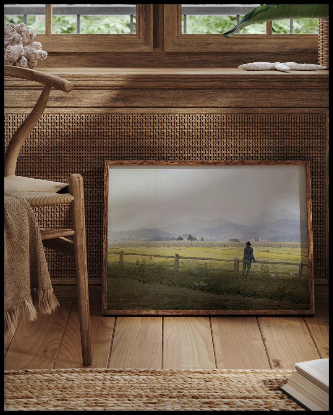 Ein gerahmter Kunstdruck von einem Feld, vor einem Fenster an die Wand angelehnt