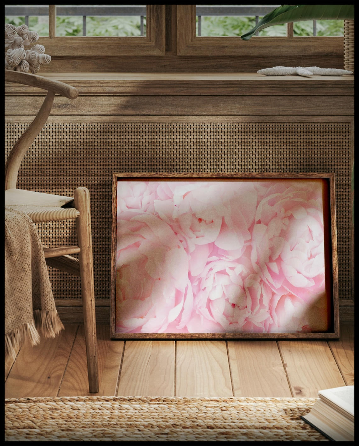 Ein gerahmtes Poster von zarten, rosa Blüten in voller Blüte, vor einem Fenster an die Wand angelehnt
