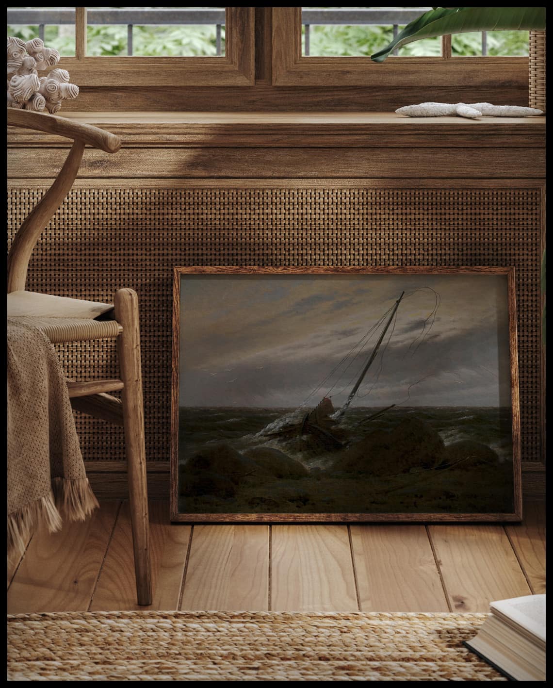 Ein gerahmter Kunstdruck von einem Holzboot, das im Sturm an einer felsigen Küste aufgelaufen ist, vor einem Fenster an die Wand angelehnt