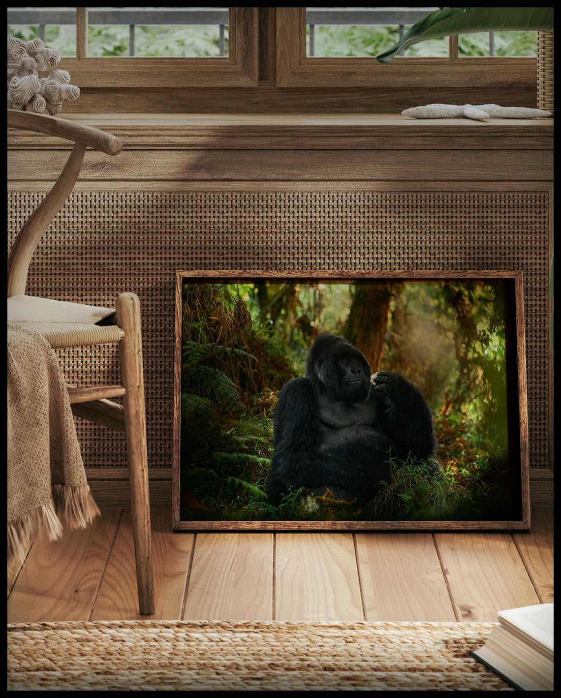 Ein gerahmtes Poster von einem Gorilla, der in einem dichten, grünen Wald sitzt, vor einem Fenster an die Wand angelehnt