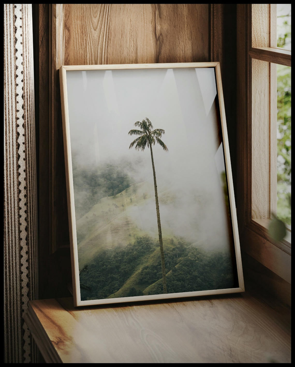 Ein gerahmtes Poster von einer hohen Palme im Nebel, vor einem Fenster an die Wand angelehnt