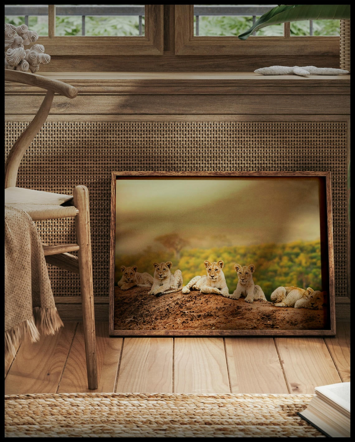 Ein gerahmtes Poster von fünf jungen Löwen, die auf einem Hügel sitzen, mit einer weiten afrikanischen Savannenlandschaft im Hintergrund, vor einem Fenster an die Wand angelehnt