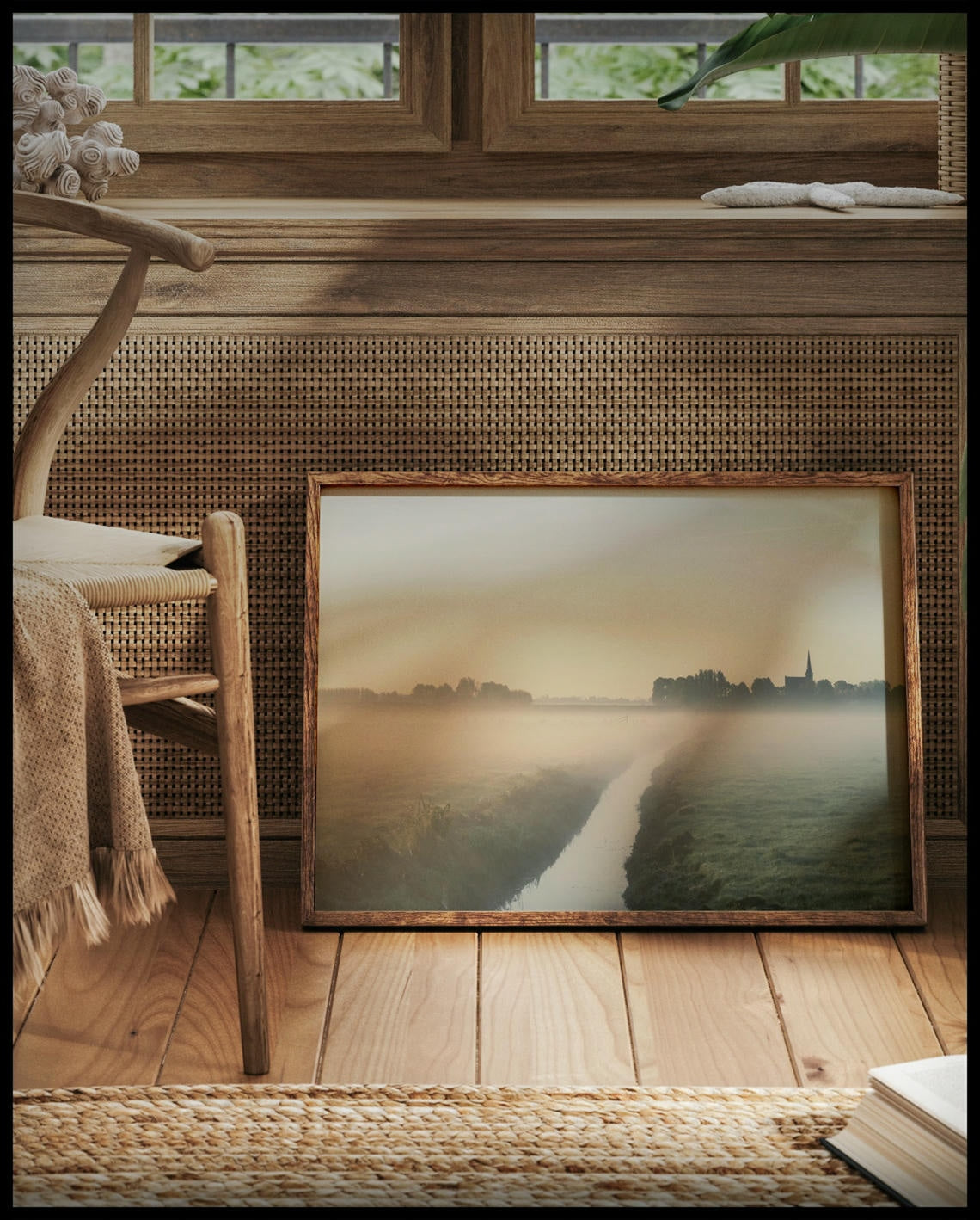 Ein gerahmtes Poster von einer nebligen Landschaft in den Niederlanden, mit einem Wasserkanal und einer Kirche im Hintergrund, vor einem Fenster an die Wand angelehnt