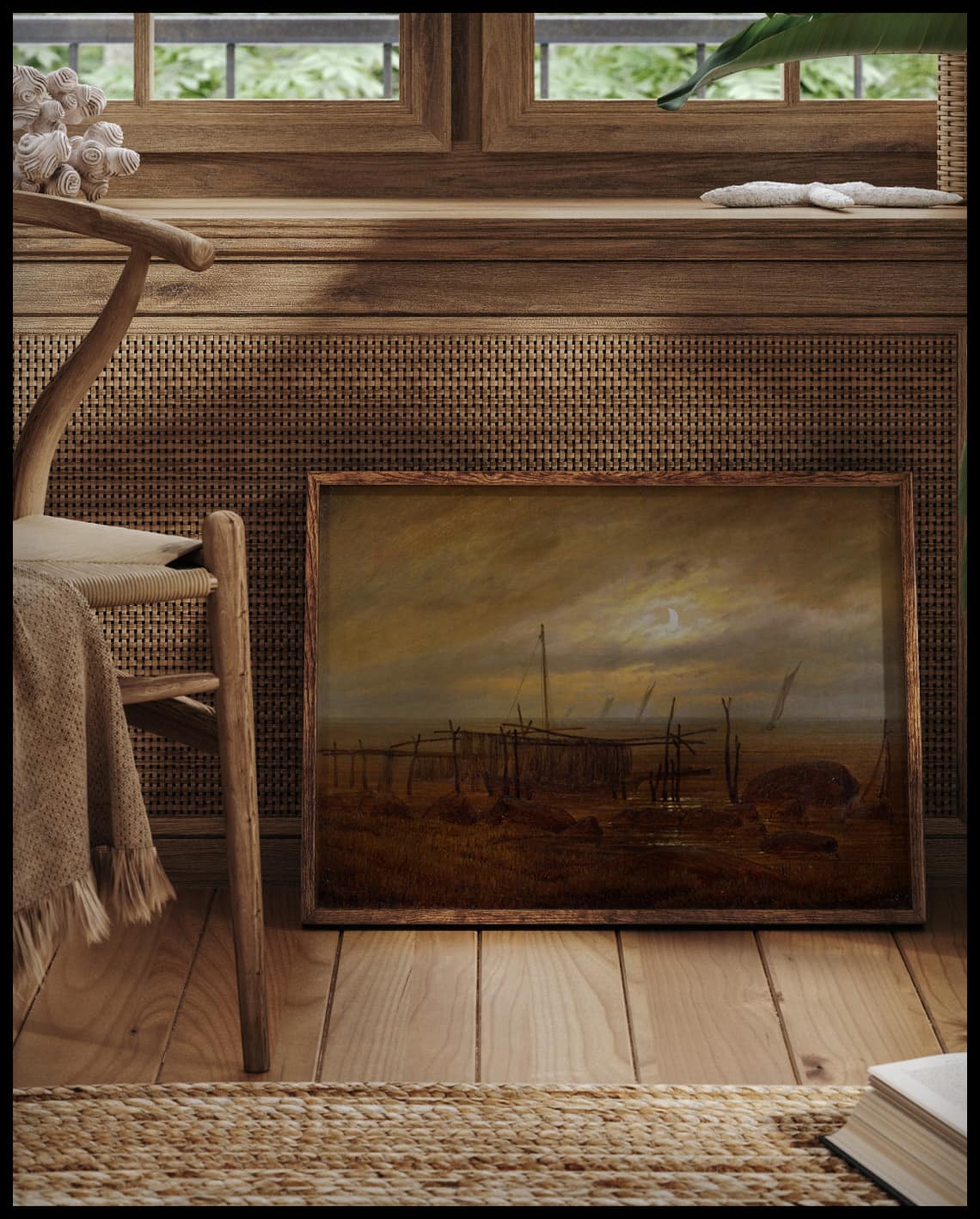 Ein gerahmter Kunstdruck von einer Küstenlandschaft im Mondschein, vor einem Fenster an die Wand angelehnt