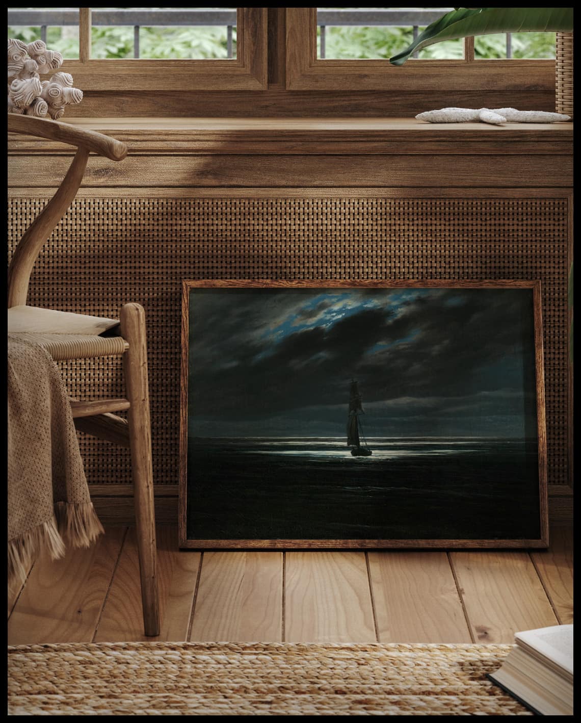 Ein gerahmter Kunstdruck von einem einzelnen Segelschiff auf dem Meer im Mondschein, vor einem Fenster an die Wand angelehnt
