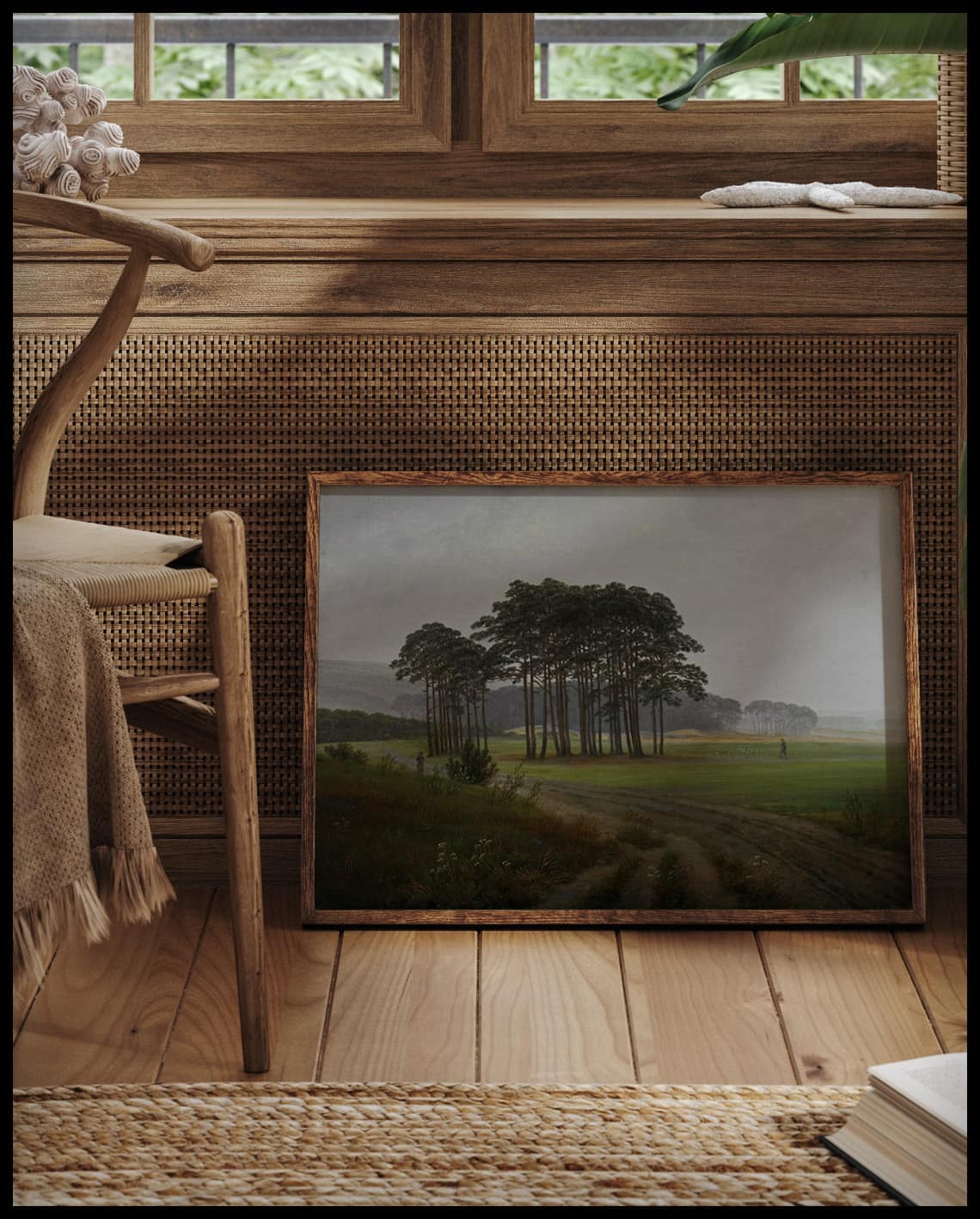 Ein gerahmter Kunstdruck von einer nebligen Wiese, einem Pfad und einem Wald im Hintergrund, vor einem Fenster an die Wand angelehnt