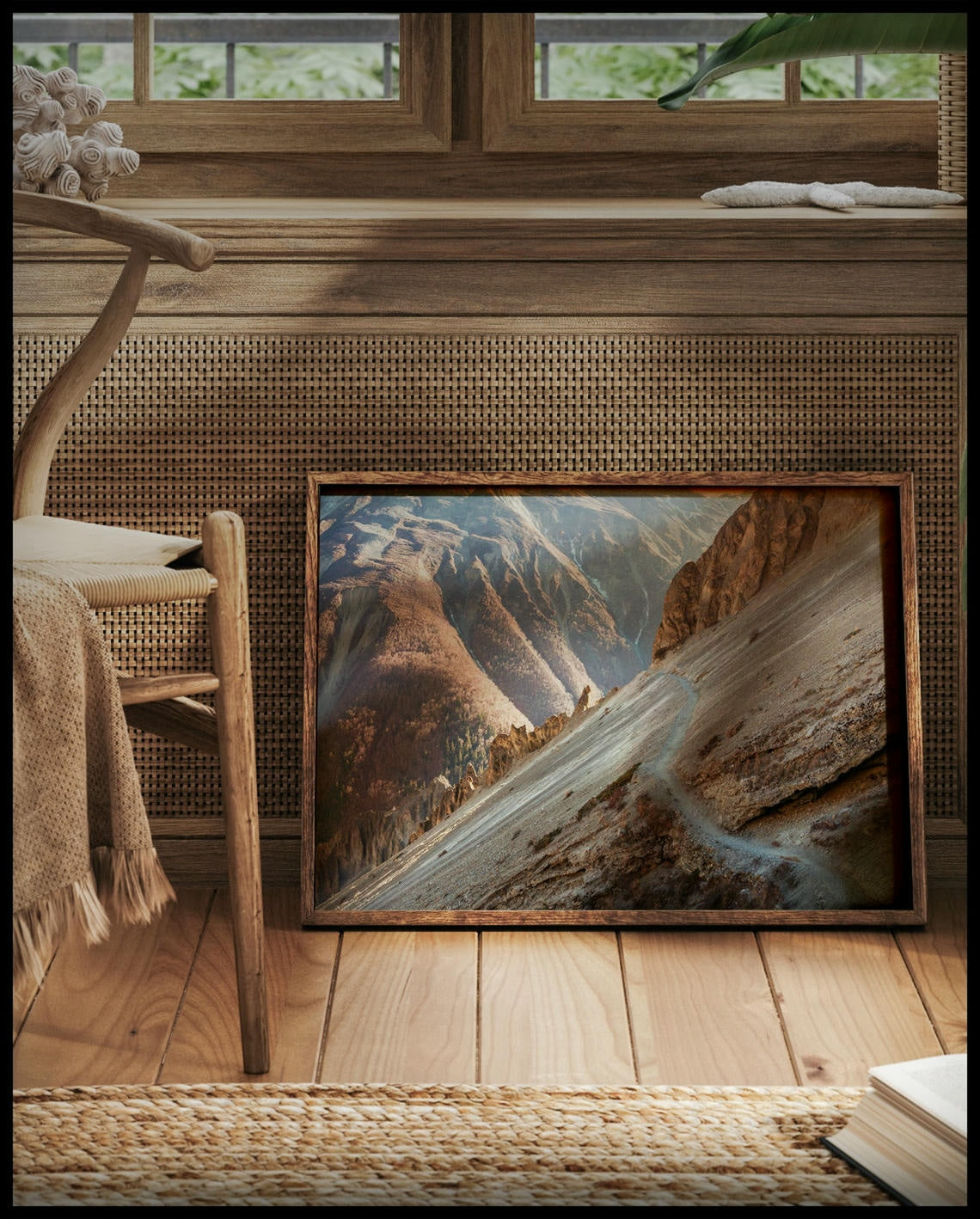 Ein gerahmtes Poster von einem Wanderweg in einer kargen, trockenen Berglandschaft, vor einem Fenster an die Wand angelehnt