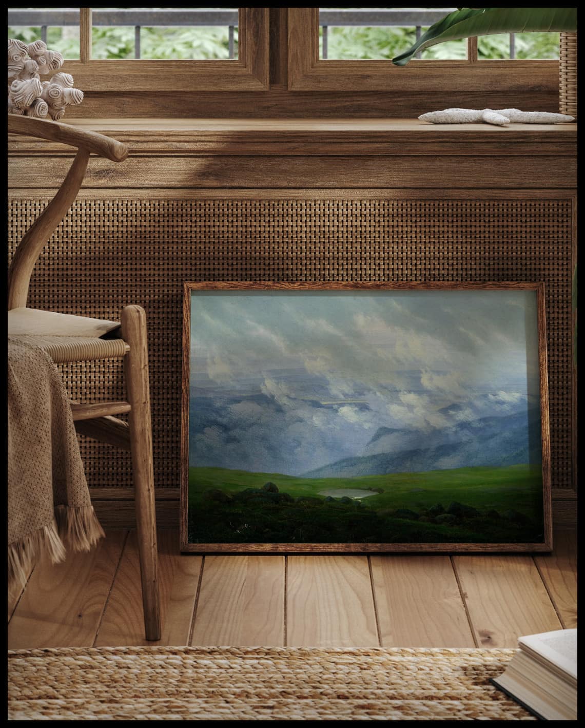 Ein gerahmter Kunstdruck von Wolken, die über die saftigen Wiesen einer Gebirgslandschaft ziehen, vor einem Fenster an die Wand angelehnt