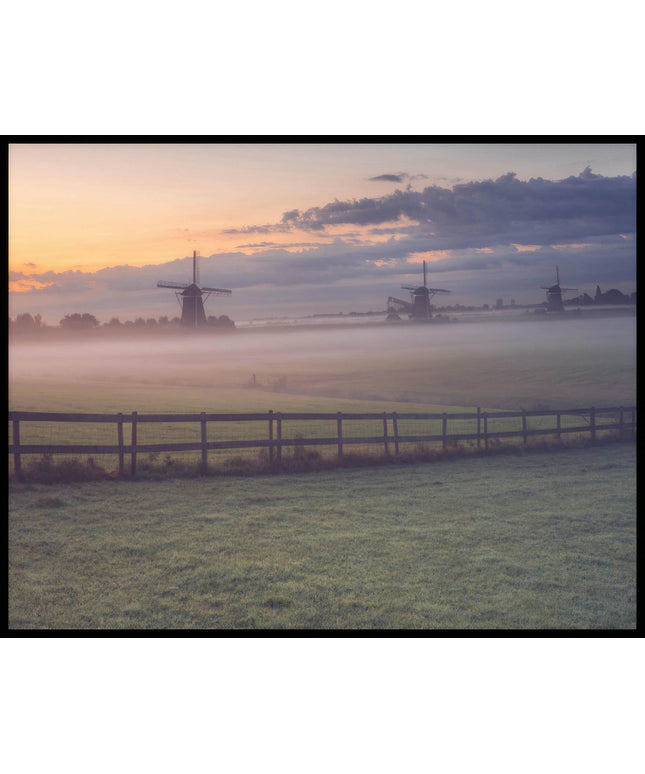 Ein Poster von einer nebligen Wiese und einem Zaun, hinter denen sich Windmühlen verbergen.