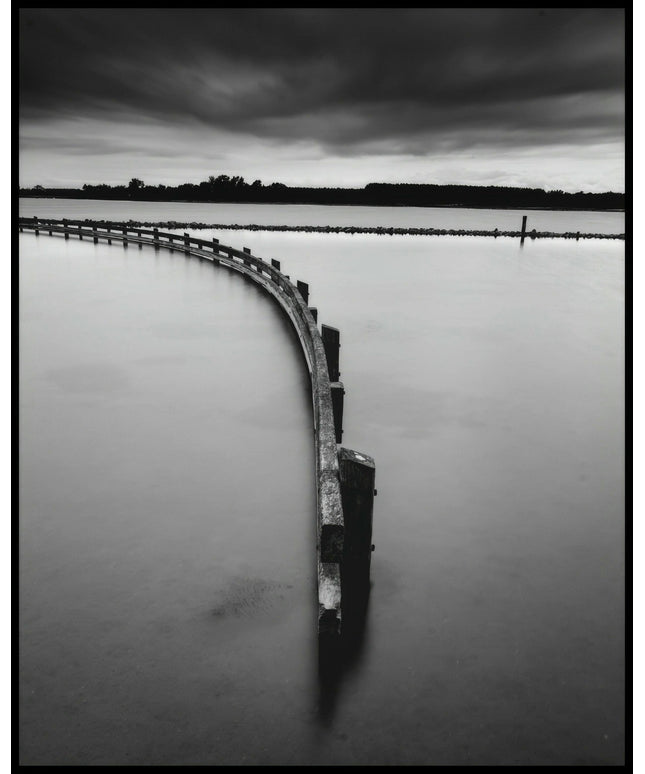 Ein Poster in schwarz-weiß von einem Zaun, der aus einem See herausragt.