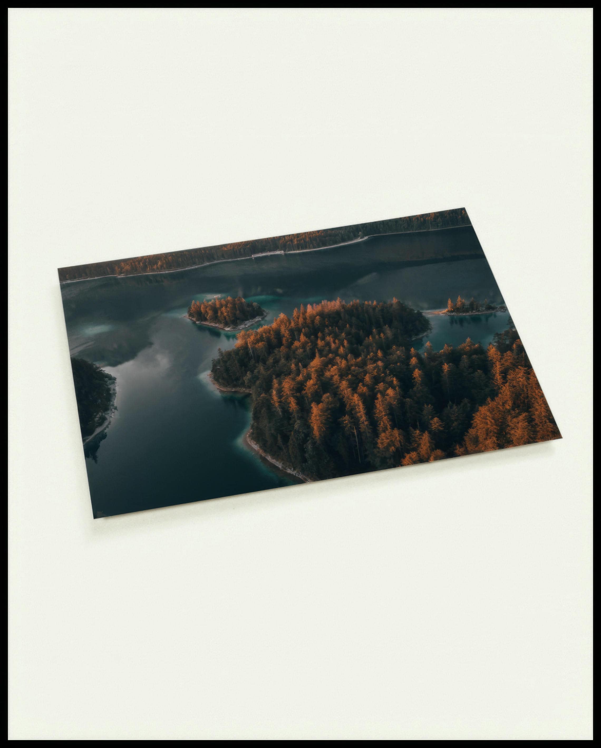 Eine Postkarte von einer Insel in einem ruhigen See, umgeben von Bäumen.