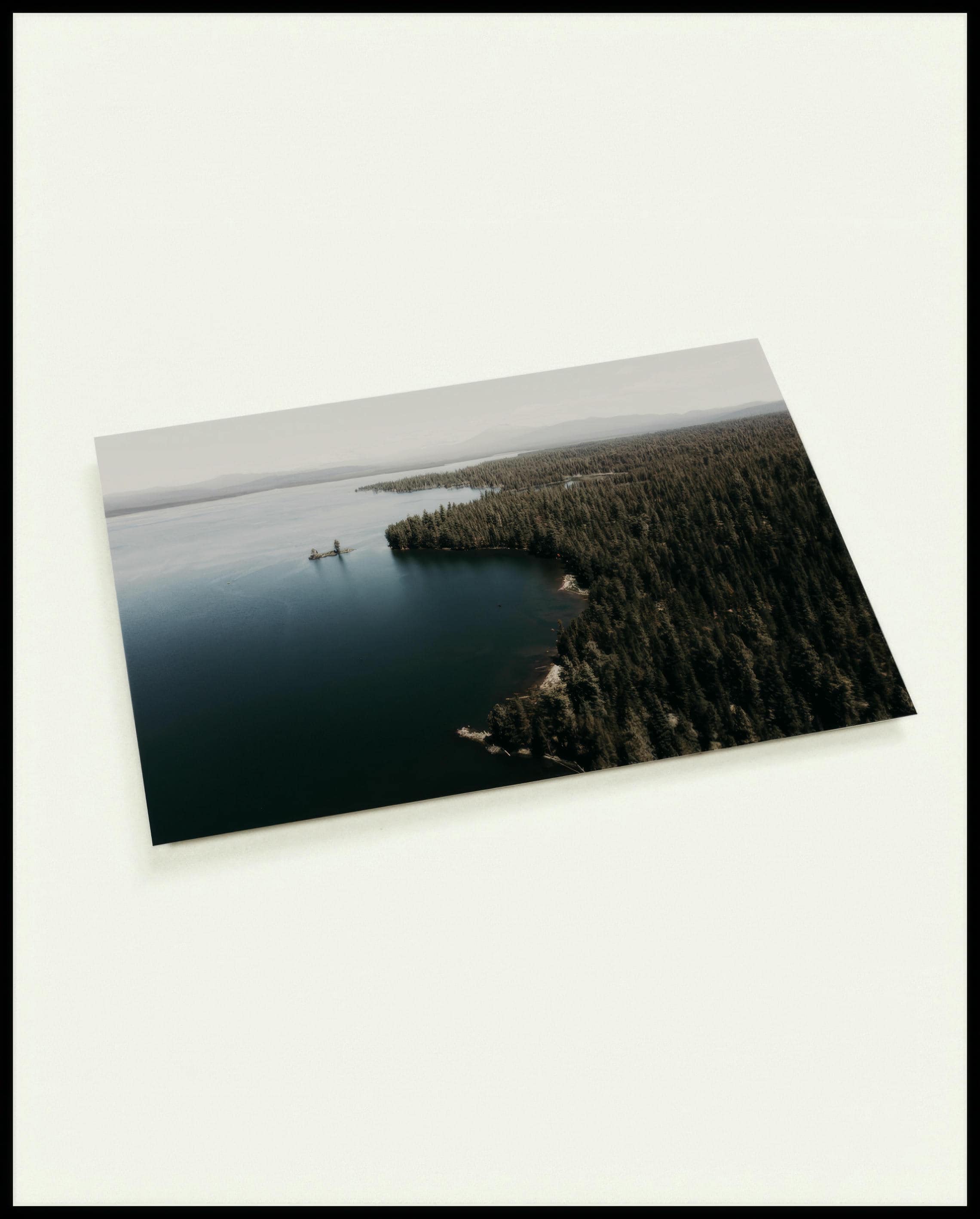 Eine Postkarte von einem See, umgeben von dichten Wäldern, aufgenommen aus der Vogelperspektive.