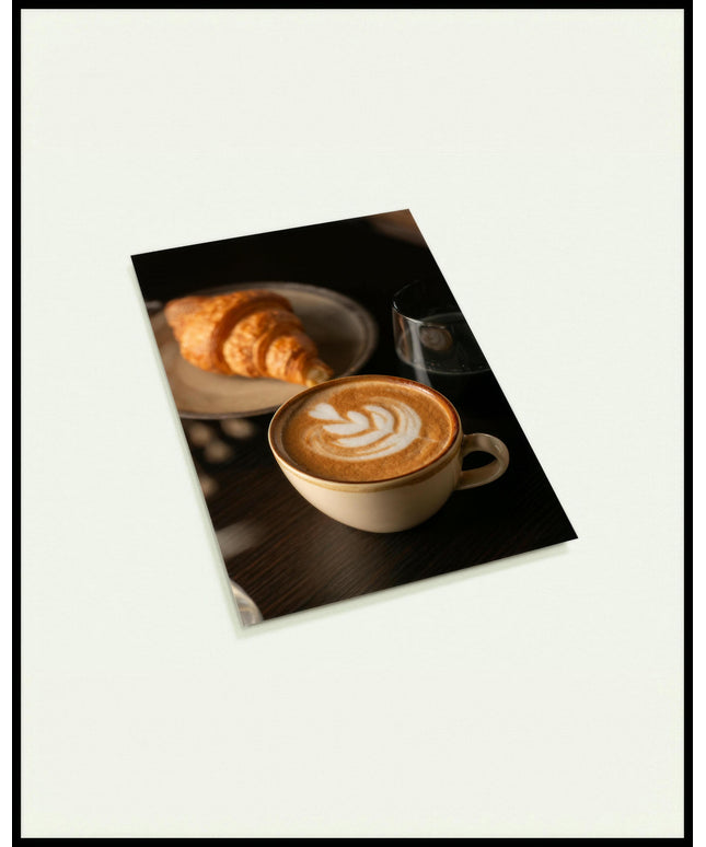 Eine Postkarte von einer Tasse Kaffee Latte neben einem Croissant und einem Glas Wasser.