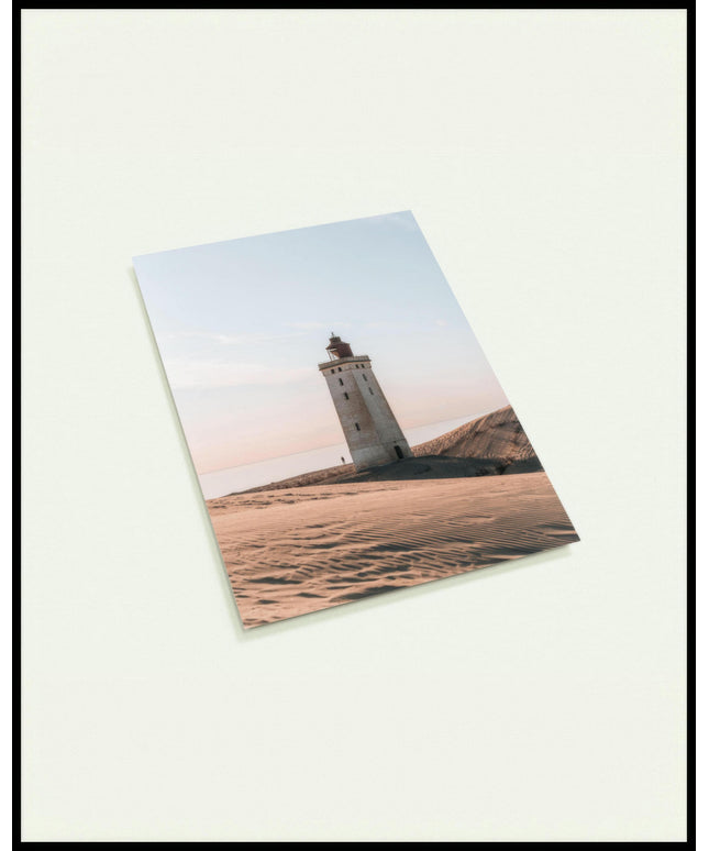 Eine Postkarte von einem einsamen Leuchtturm in einer sandigen Dünenlandschaft unter einem klaren Himmel.