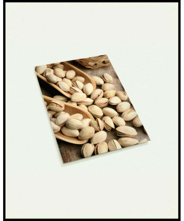 Eine Postkarte von Pistazien die auf einem Tisch und auf einer Schippe liegen.