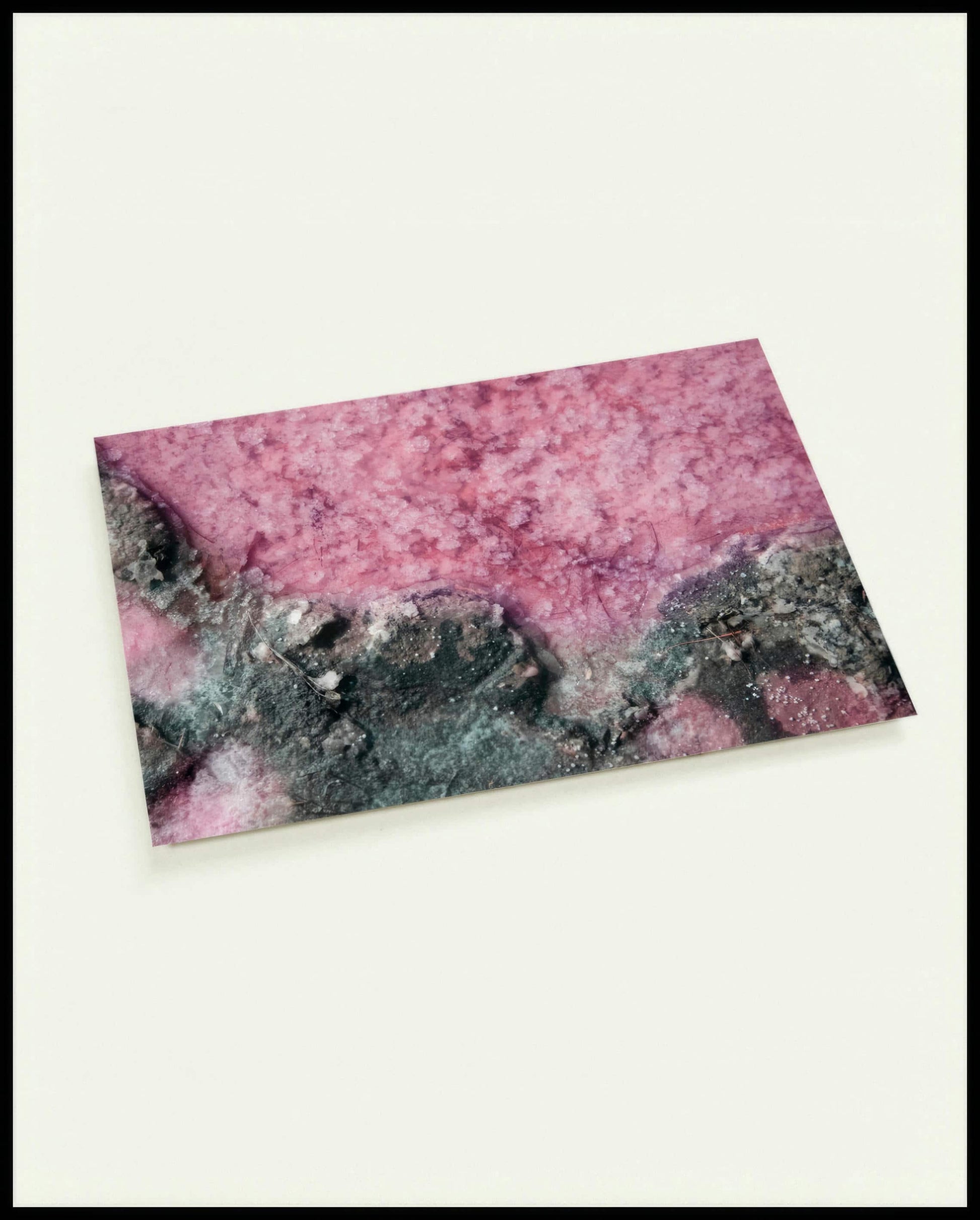 Eine Postkarte von rosa Salz und dunklem Gestein.
