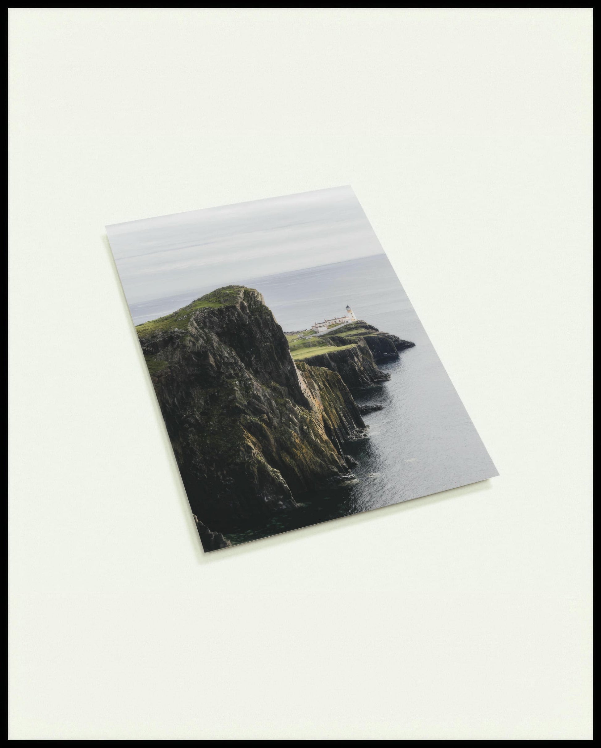 Eine Postkarte von einer kargen Klippe in Schottland mit einem Leuchtturm.