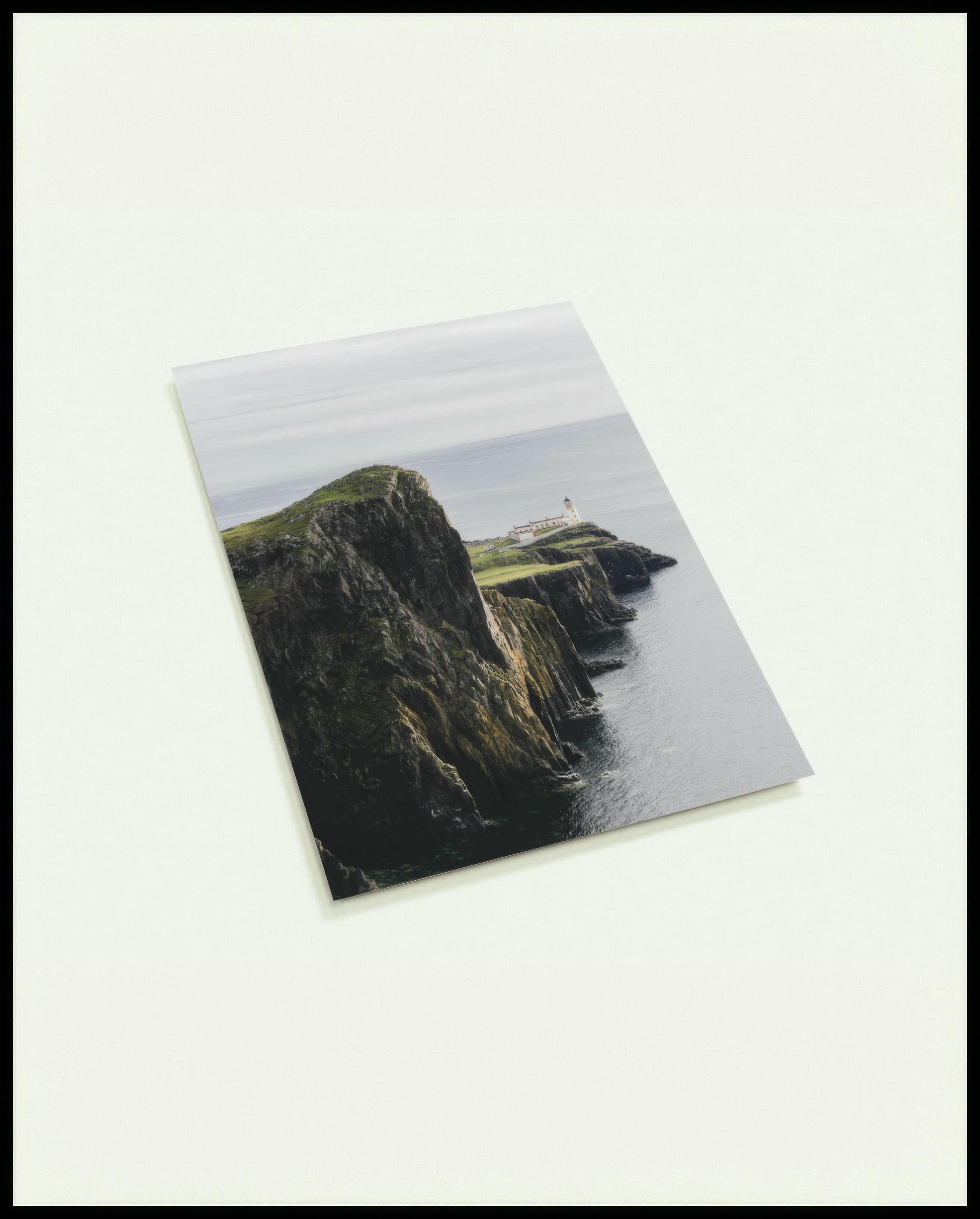 Eine Postkarte von einer kargen Klippe in Schottland mit einem Leuchtturm.