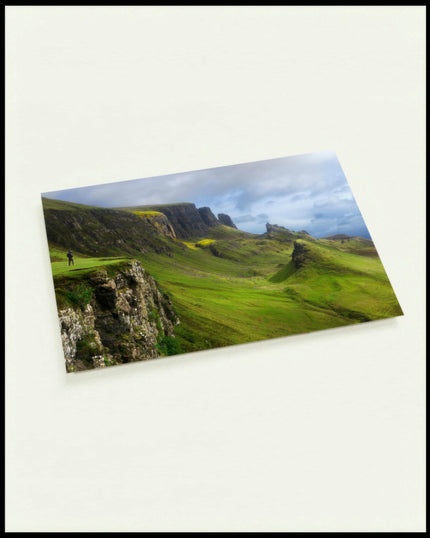 Eine Postkarte von kargen Bergformationen mit grünem Gras.