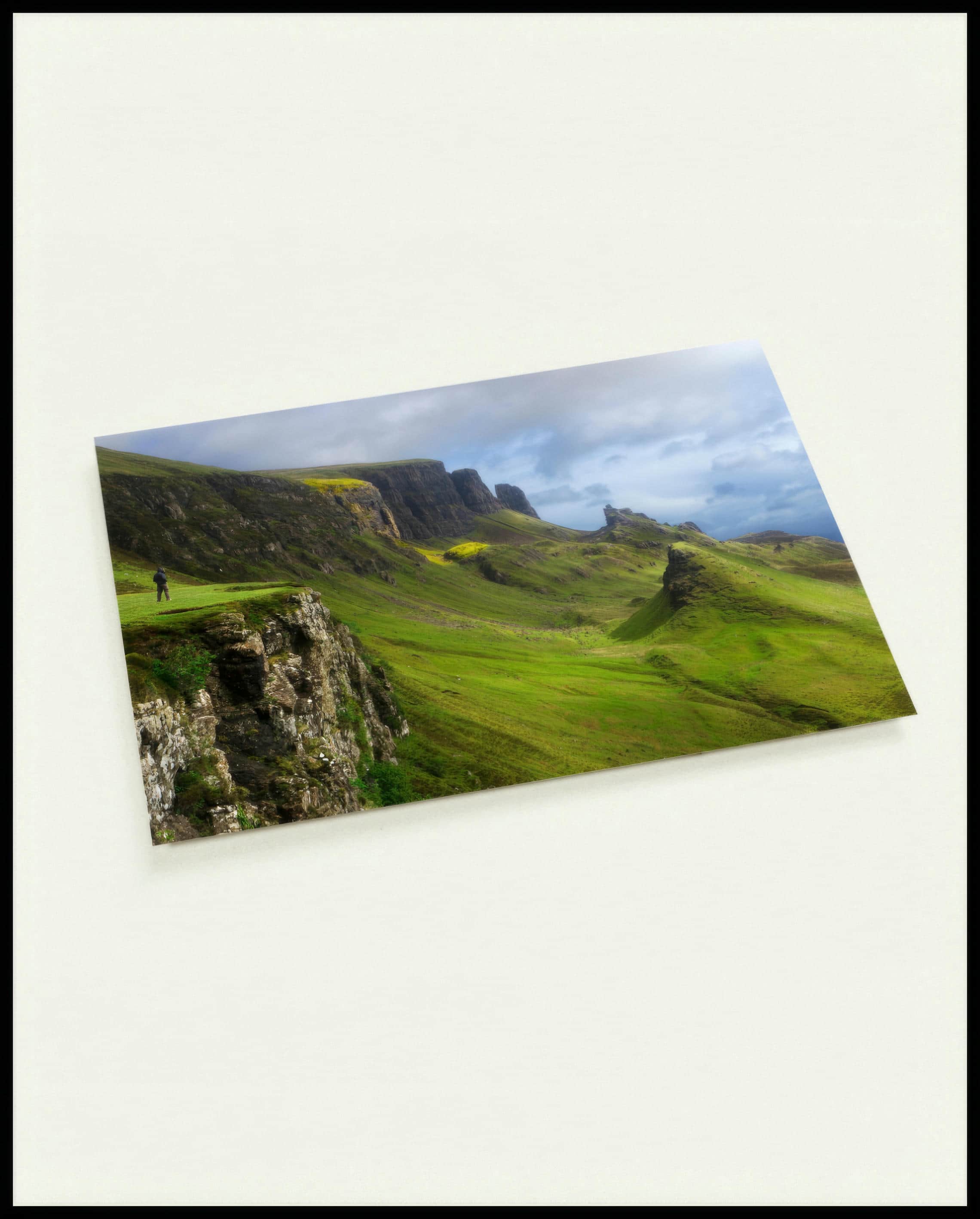Eine Postkarte von kargen Bergformationen mit grünem Gras.