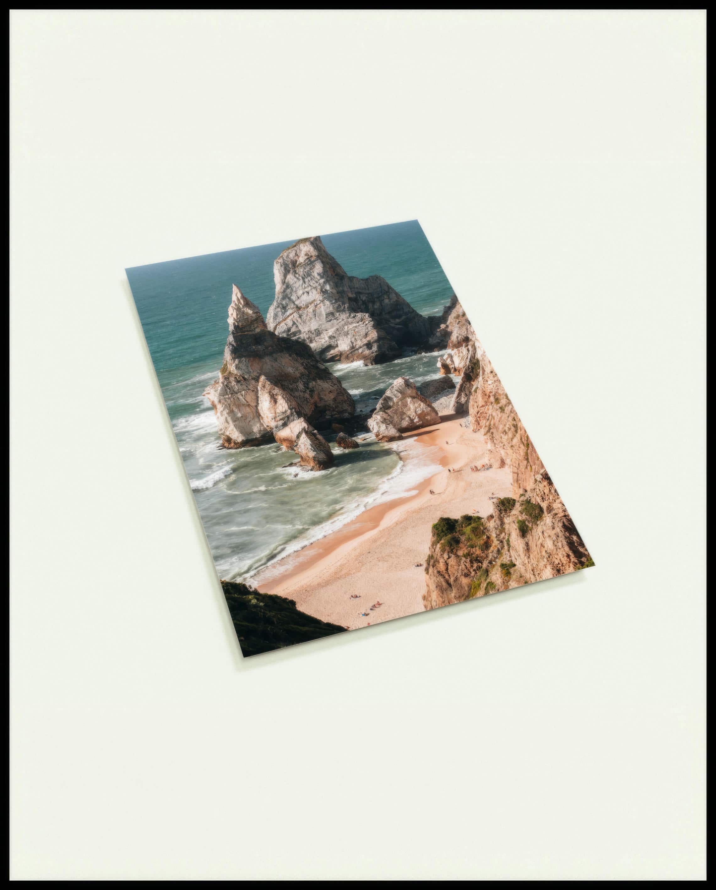 Eine Postkarte von hohen Felsformationen im Meer an einem Strand.