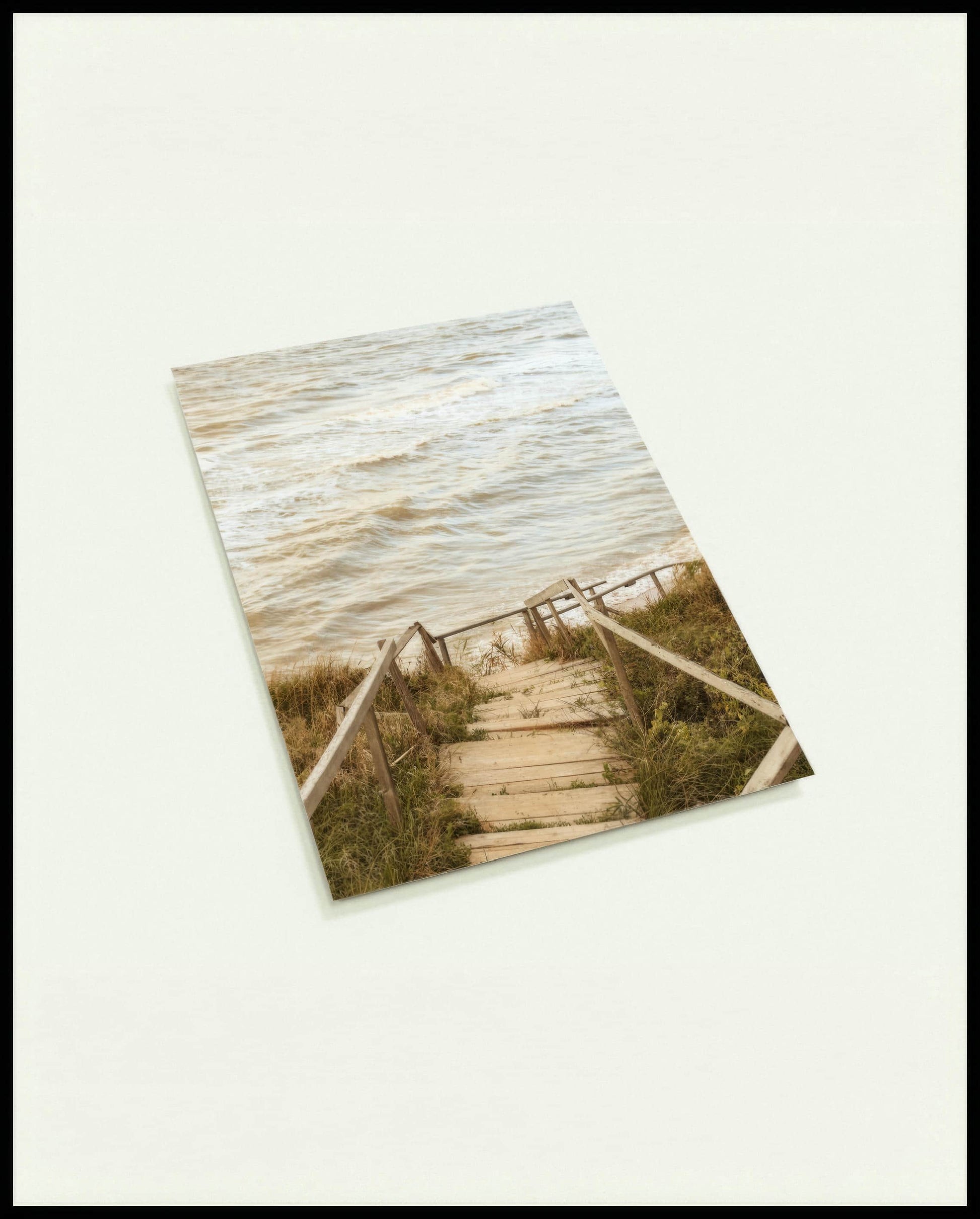 Eine Postkarte von einer Holztreppe die durch Dünen runter zum Strand führt.