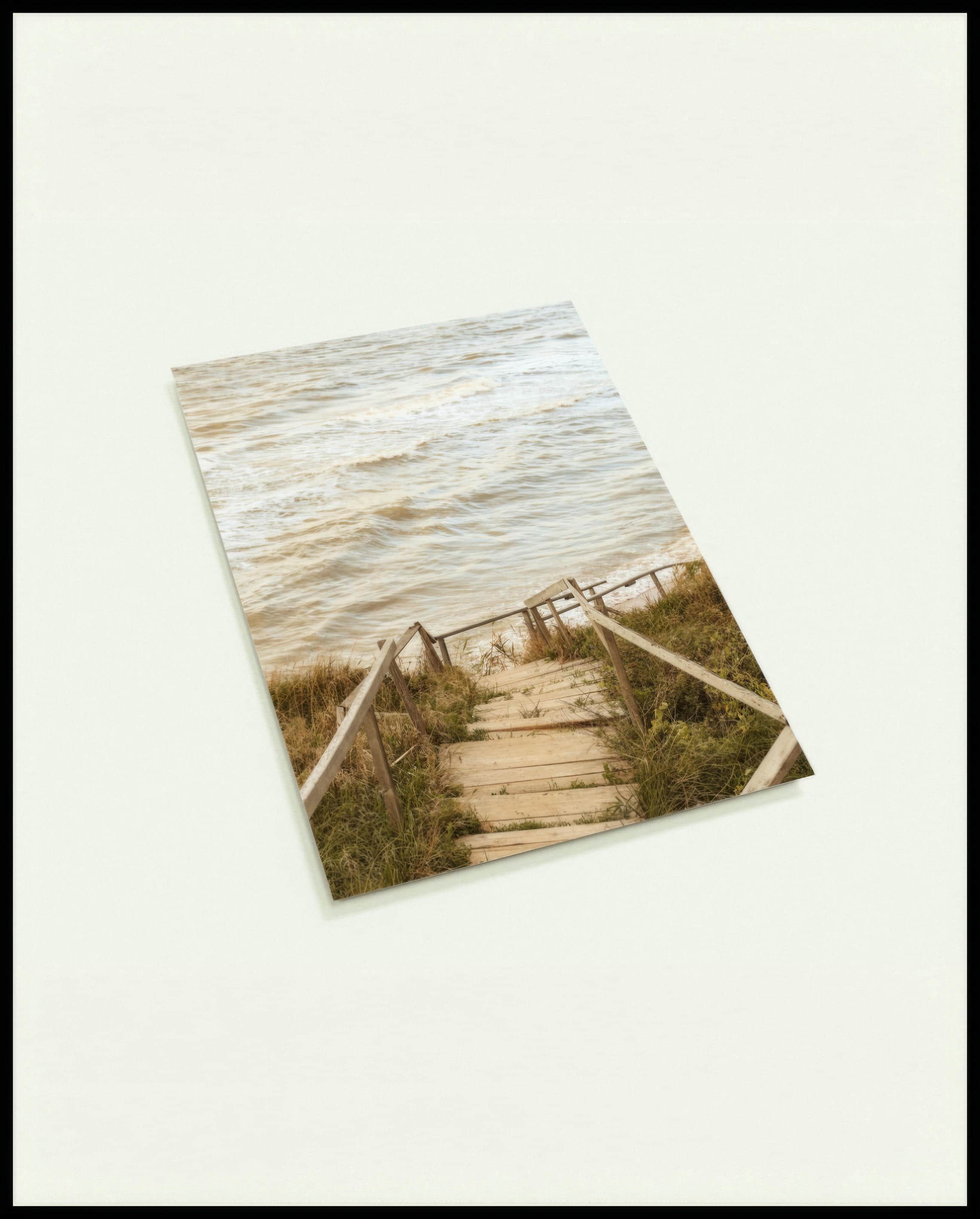 Eine Postkarte von einer Holztreppe die durch Dünen runter zum Strand führt.