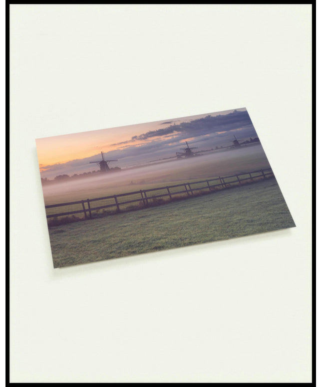 Eine Postkarte von einer nebligen Wiese und einem Zaun, hinter denen sich Windmühlen verbergen.